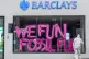 An activists spray paints the windows of a Barclays in Claph