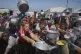 Palestinians struggle to receive cooked food distributed at a community kitchen in the Muwasi area of Khan Younis, in the Gaza Strip, May 23, 2025