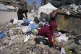 Islam Abu Taeima, a 40-year-old mother of five (left), and a boy look for some food on a pile of garbage in Gaza City, May 25, 2025
