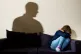 A shadow of a man as a woman cowers in the corner