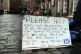 A sign near a homeless person and their dog on the Royal Mile in Edinburgh