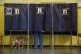 A dog on a leash waits as its owner votes in a booth for referendums on citizenship and job protections, at a polling station in Milan, Italy, June 8, 2025