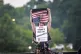 A demonstrator holds a distressed American flag and a sign reading 