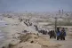 Displaced Palestinians, carrying their belongings move between southern and northern Gaza along a beach road, in the outskirts of Gaza City, on March 21, 2025