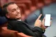 Former Brazilian President Jair Bolsonaro shows his cell phone during his Supreme Court trial as he and others face charges for an alleged coup plot to keep him in office after his 2022 election defeat, in Brasilia, Brazil, June 10, 2025