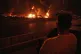 A man looks at flames rising from an oil storage facility after it appeared to have been struck by an Israeli strike in Tehran, Iran, June 15, 2025