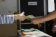 Ballot papers are handed over to a citizen (left) to vote on referendums on citizenship and job protections, at a polling station in Rome, June 8, 2025