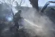 A volunteer firefighter sprays water with a hose as a wildfire burns in Rafina, east of Athens, Greece, July 3, 2025, with several houses destroyed by the fire in the area