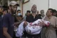 A Palestinian man carries the body of his child, who was killed by an Israeli military air strike on Gaza, at Shifa Hospital in Gaza City, July 12, 2025