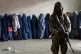 A Taliban fighter stands guard as women wait to receive food rations distributed by a humanitarian aid group in Kabul, Afghanistan, May 23, 2023