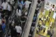 People take escalators as shoppers, at right downstairs, select clothing at a fashion boutique store inside a shopping mall, in Beijing on July 13, 2025