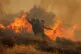 Firefighter uses a hose as the try to extinguish the blaze near the town of Ierapetra on the south coast of Crete island, Greece, July 3, 2025, as a fast-moving wildfire prompted authorities to clear villages and coastal areas, officials said