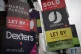Various 'for sale', 'sold' and 'let by' estate agent signs juxtaposed next to a Dreams store in Clapham, London