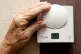 An elderly lady adjusting her thermostat on at home in Liverpool