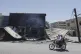 Syrian citizens ride in front of a shop that was burned during clashes between Syrian government forces and Druze militias on the outskirts of Sweida city, southern Syria, July 16, 2025