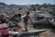 A Palestinian boy walks amid debris after Israeli military strikes in a tent camp for displaced people near Al-Aqsa Hospital, in Deir al-Balah, August 21, 2025