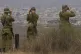 Israeli soldiers uses binoculars to look at damaged buildings in the Gaza Strip, from southern Israel, Wednesday, Aug. 13, 2025