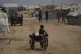 A Palestinian girl pushes a cart loaded with jerrycans of water after collecting it at a camp for displaced people in Khan Younis, Gaza Strip, August 13, 2025