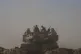 Israeli soldiers sit on the top of tank parked on an area near the Israeli-Gaza border, as seen from southern Israel, Monday, Aug. 18, 2025
