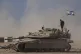 An Israeli soldier stands on the top of a tank parked on an area near the Israeli-Gaza border, as seen from southern Israel, August 20, 2025