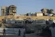 Palestinians walk on an area at a makeshift tent camp located next to buildings destroyed during Israeli air and ground operations, in Gaza City, August 23, 2025