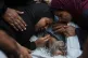 Palestinian women mourn over the body of their father, Abd Rahman Al-Baba, who was killed while trying to reach aid trucks entering northern Gaza Strip through the Zikim crossing with Israel, at Shifa Hospital in Gaza City, August 4, 2025