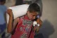 A Palestinian boy carries a sack of flour unloaded from a humanitarian aid convoy en route to Gaza City from the northern Gaza Strip, July 31, 2025