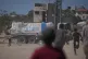 Palestinians rush toward trucks carrying aid from the World Food Programme (WFP) as they drive through Deir al-Balah in central Gaza, October 15, 2025