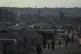 Displaced Palestinians walk through a tent camp adjacent to destroyed homes and buildings in Khan Younis, Gaza Strip, October 18, 2025