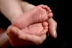 A mother holding the feet of her new born baby in her hand