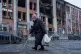 An elderly woman walks on a street in front of a building, damaged by a Russian strike, in Kyiv, Ukraine, December 1, 2025