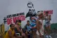 People sit near a mural of former President Nicolas Maduro with a message that reads in Spanish: 