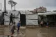 Displaced Palestinian children walk through a rain-soaked tent camp following heavy rainfall in Deir al-Balah, central Gaza Strip, March, 26, 2026