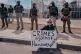 A protester holds a sign as ICE agents stand guard outside the Delaney Hall detention during a protest against the transfer of detainees, May 26, 2026, in Newark, N.J.