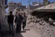 Palestinian Yusuf Abu Hamam (front, centre) who was expelled from his town during the first Israeli-Arab war in 1948, walks with his grandchildren and son past buildings destroyed by the Israeli air and ground operations in the Shati refugee camp in Gaza