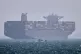 A container ship sits at anchor as a small motorboat passes in the foreground in the Strait of Hormuz off Bandar Abbas, Iran, May 2, 2026