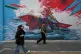 People walk past a mural depicting a U.S. aircraft carrier under missile attack in downtown Tehran, Iran, May 17, 2026