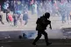 A police officer runs after launching tear gas at protesters during an anti-government demonstration in La Paz, Bolivia, May 25, 2026