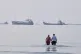 Two men wade in the waters of the Strait of Hormuz with vessels anchored in the background, off Bandar Abbas, Iran, July 12, 2026