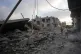 Palestinians walk past destroyed buildings following an Israeli airstrike last night, at al-Maghazi refugee camp, central Gaza Strip, July 16, 2026