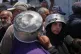 Displaced Palestinians lineup to receive donated food at a community kitchen in Khan Younis, southern Gaza Strip, July 23, 2026