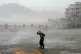 In this photo released by Xinhua News Agency, a man walks against strong wind and rain as Typhoon Dolphin makes landfall at Dongsha community in Yuhuan, Taizhou, eastern China's Zhejiang Province, August 9, 2026