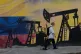 A pedestrian walks past a mural featuring oil wells in Caracas, Venezuela