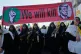 Women affiliated with Iran's Revolutionary Guard carry rifles as they march beneath a banner depicting U.S. President Donald Trump in crosshairs and reading 