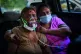 An Indian woman breathes using an oxygen mask as she waits f
