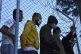 Migrants inside a refugee camp watch the visit of EU Commiss