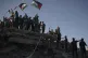 Protesters wave Palestinian flags as they stand atop the rub