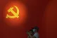 People stand near a Communist Party's flag on display at an 