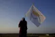 A man with a Cyprus flag stands in front of the Varosha or F