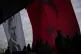 People walk past a giant Turkish flag and a portrait of Must